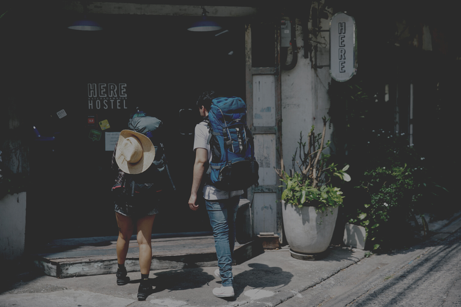 Unrecognizable couple of travellers with backpacks entering hotel